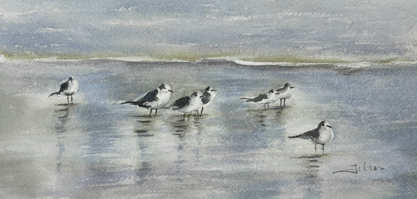 A watercolor painting depicting a group of sea gulls standing on a shimmering shoreline with gentle waves and a soft blue sky in the background.